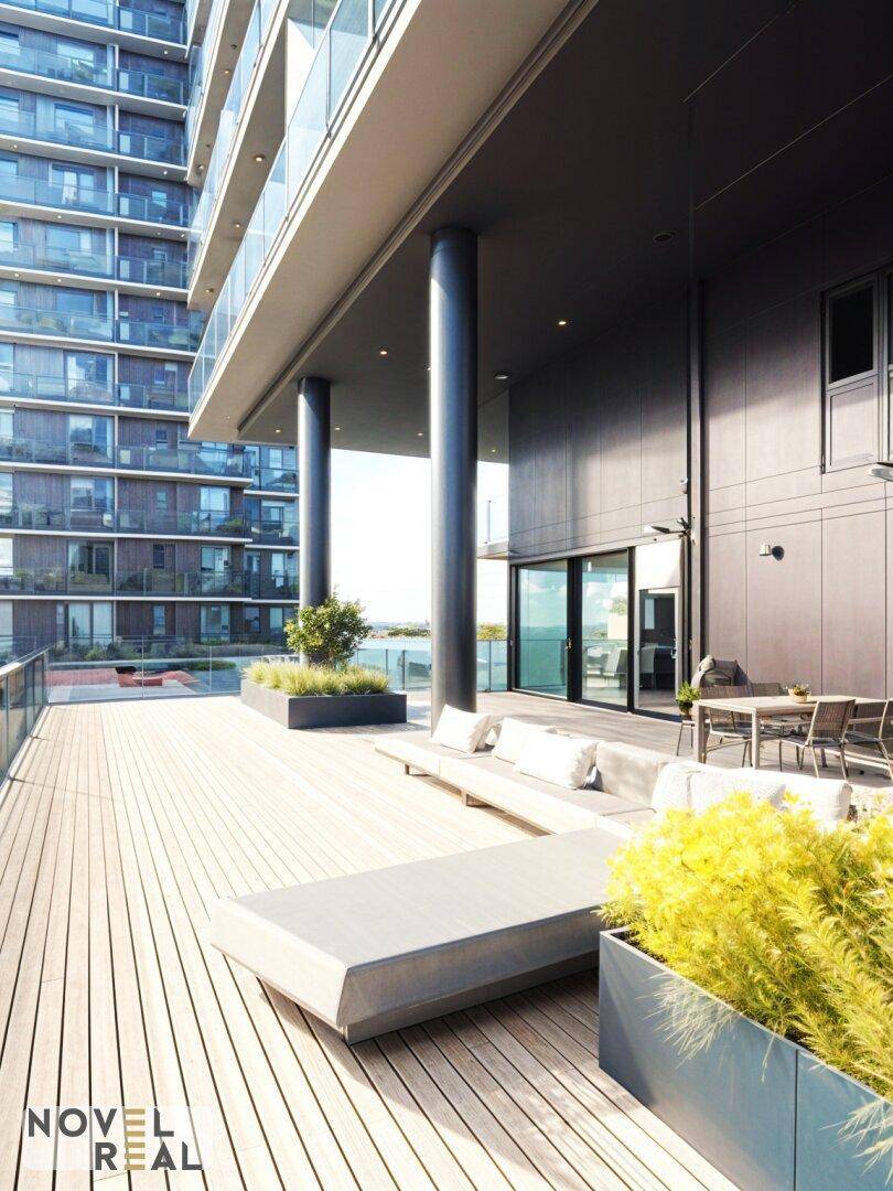Große, moderne Terrasse mit Holzdeck, Lounge-Möbeln und Blick auf die umliegenden Gebäude.