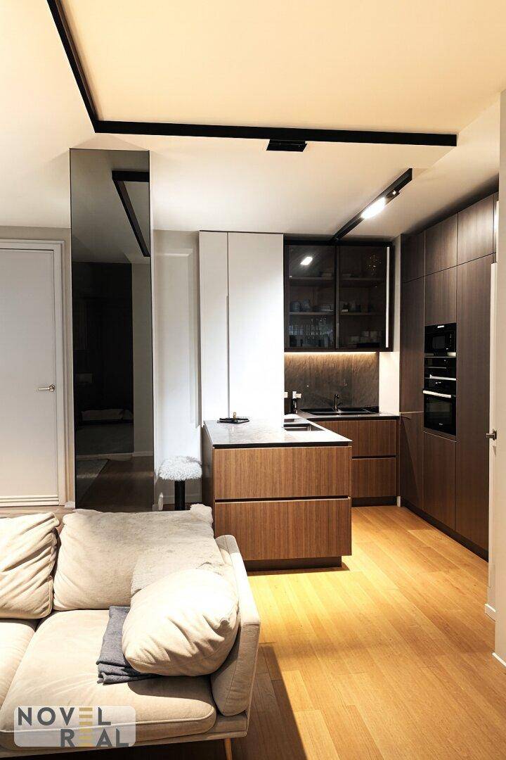 Moderne Küche mit Holzschränken, Kücheninsel und integrierten Geräten im offenen Wohnbereich.