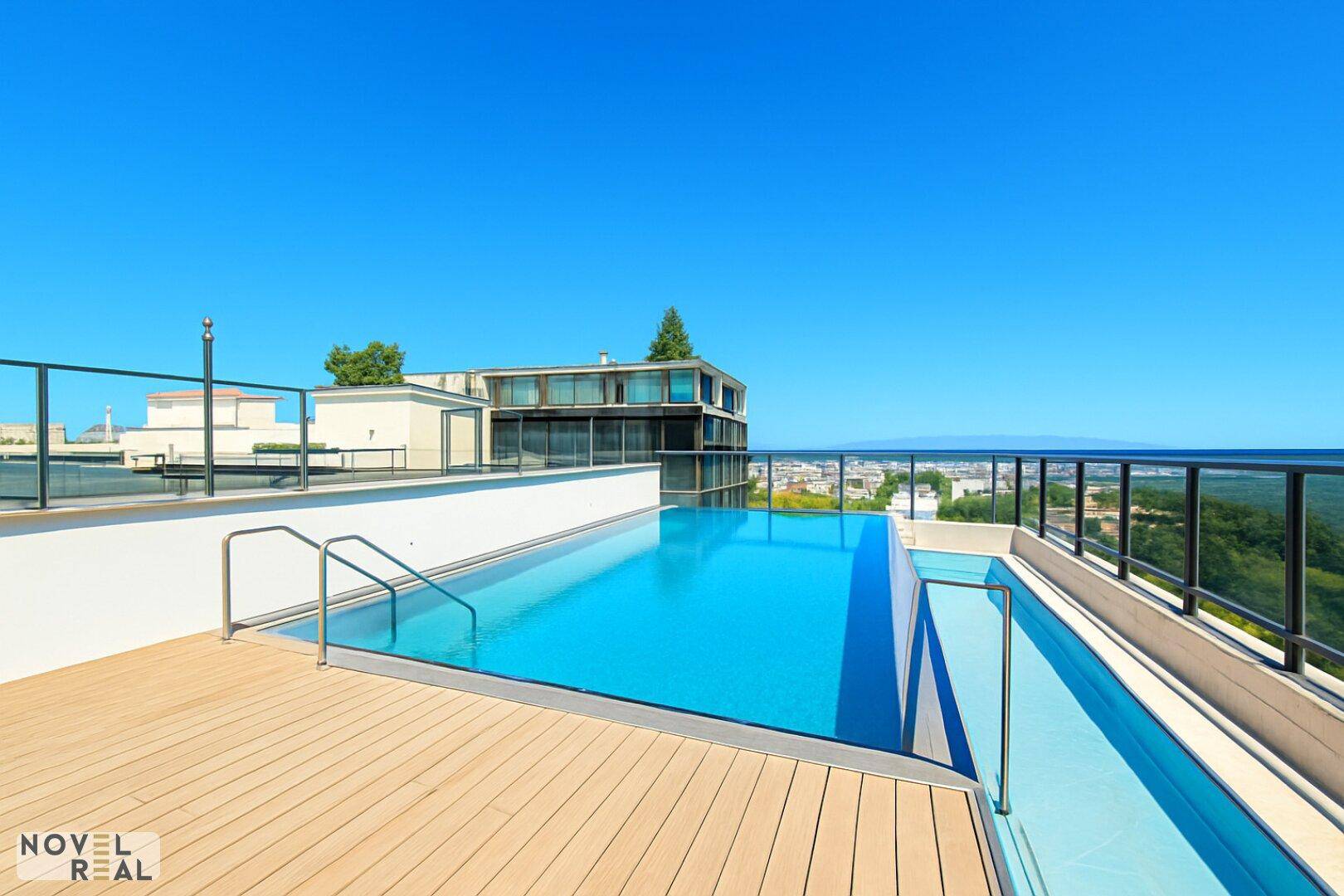 Infinity-Pool auf der Dachterrasse mit weitem Blick über die Stadt und die Landschaft.