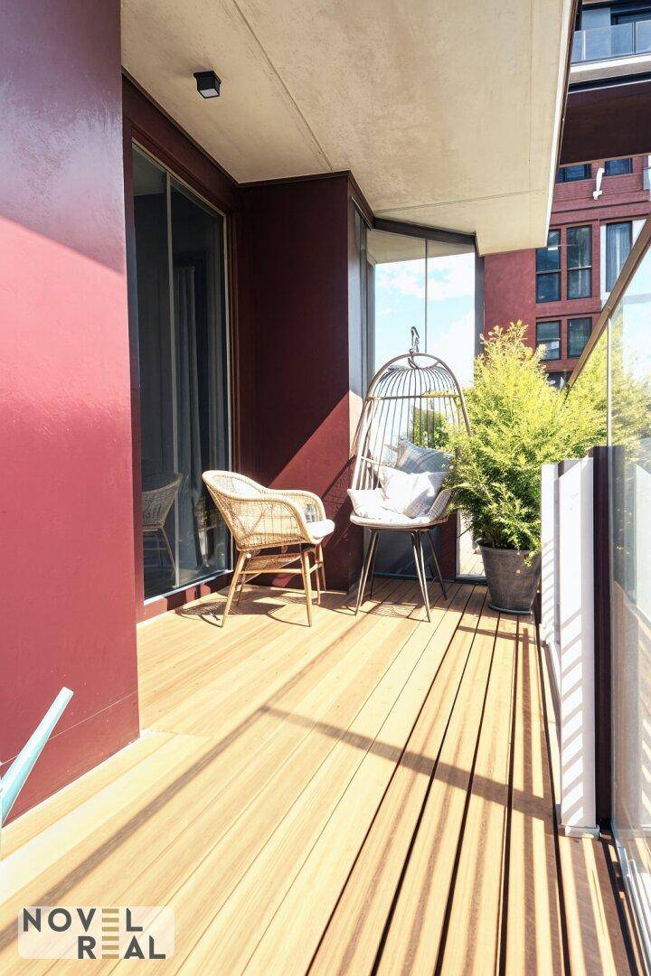 Gemütlicher Balkon mit Holzfußboden, Sitzgelegenheiten und Pflanzen für entspannte Stunden.