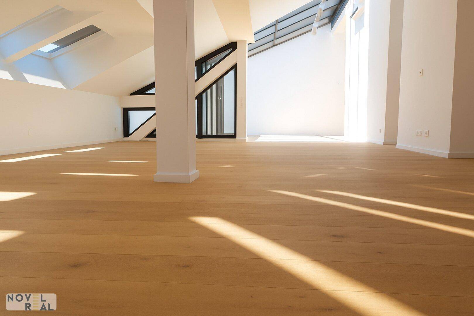 Heller und offener Wohnbereich mit Holzboden, hohen Decken und großen Fenstern.