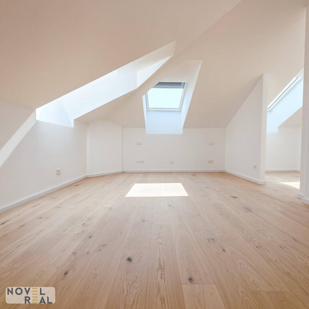 Heller Raum mit Holzboden und Dachfenster, das den Raum mit natürlichem Licht füllt.