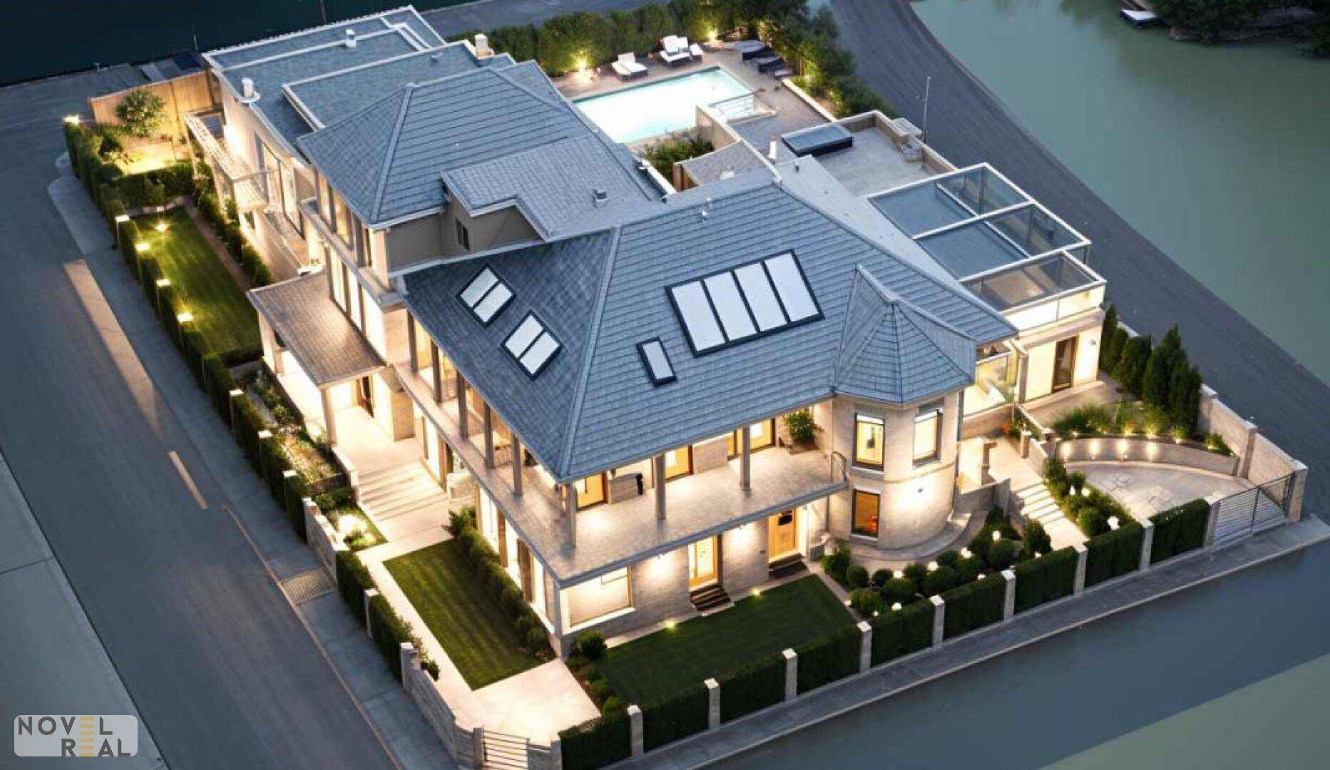 Luftaufnahme einer weitläufigen Luxusvilla mit Pool, Dachterrassen und gepflegtem Grundstück am Wasser.