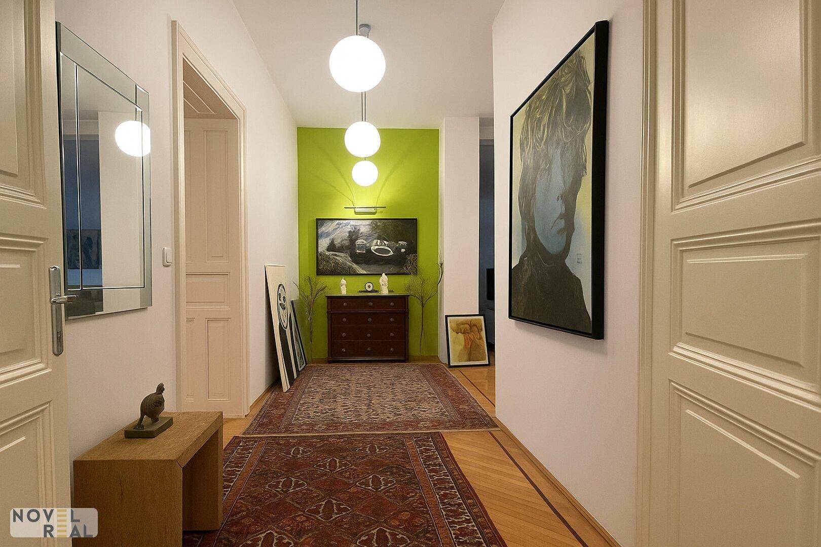 Heller Flur mit Parkettboden, einem grünen Akzentwand und moderner Kunst, die den Raum belebt.