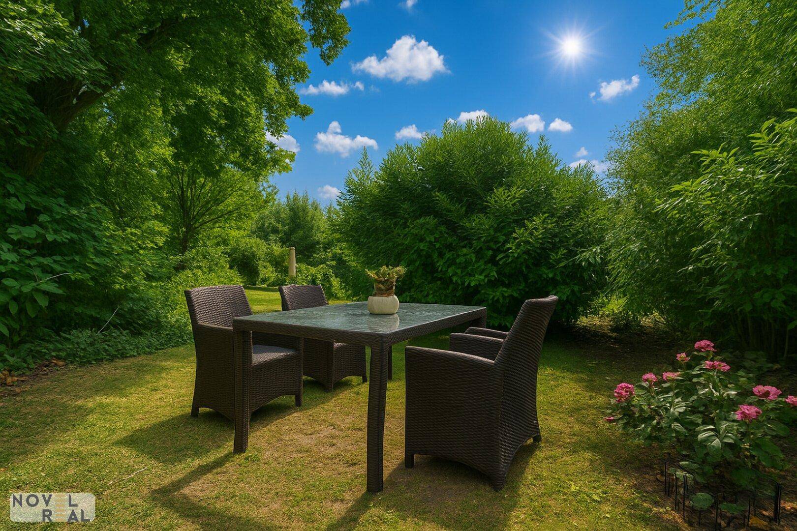 Gemütlicher Sitzbereich im Garten mit Tisch und Stühlen, umgeben von Bäumen und blühenden Pflanzen.