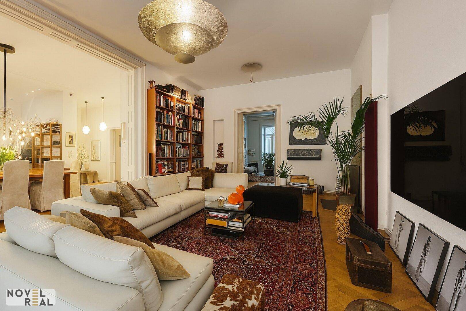 Geräumiges Wohnzimmer mit großem Sofa, Bücherregal und offener Verbindung zum Essbereich.