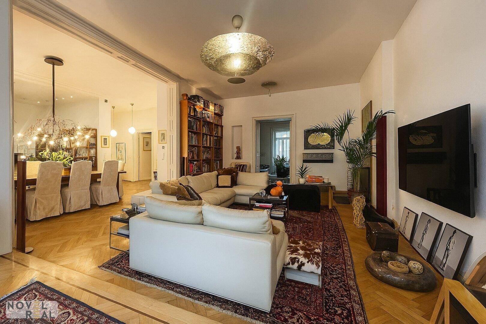 Großzügiges Wohnzimmer mit bequemer Sitzecke, Bücherregal und Blick auf den Essbereich.