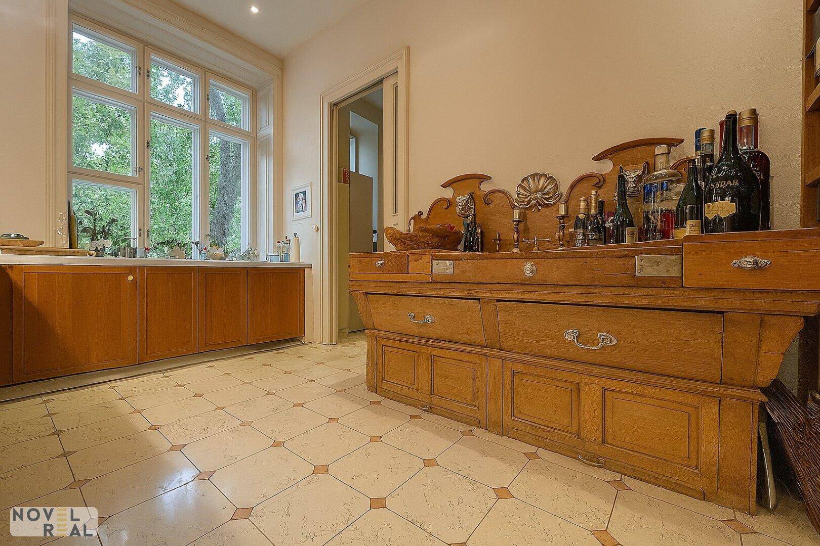 Geräumige Küche mit traditionellen Holzmöbeln und großem Fenster, das viel Tageslicht hereinlässt.