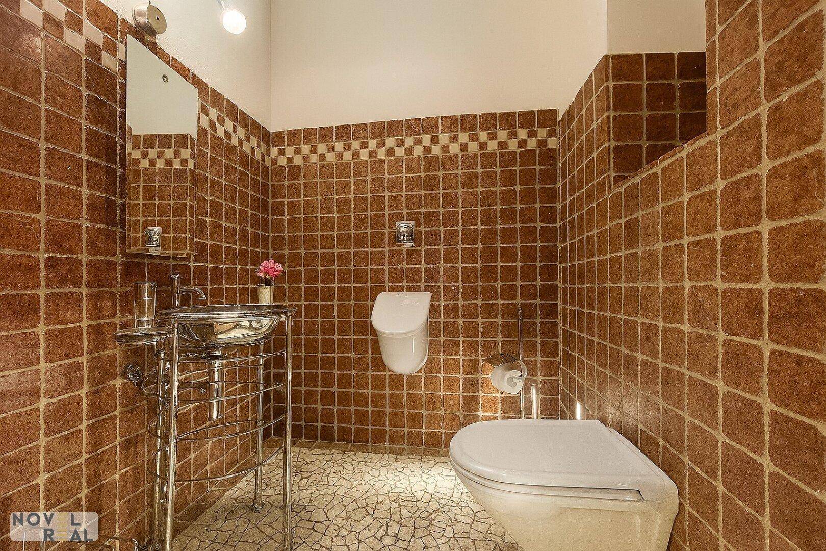 Separate Toilette mit Urinal, Waschbecken und braunen Wandfliesen im klassischen Stil.