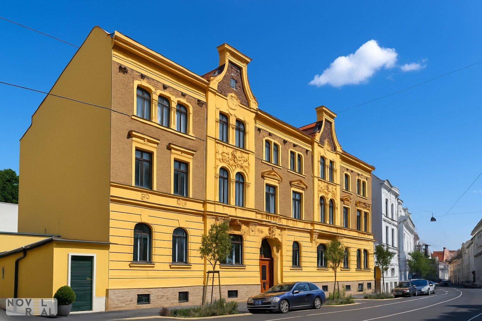 Historisches Gebäude mit gelber Fassade und gepflegter Straßenansicht in der Stadt.