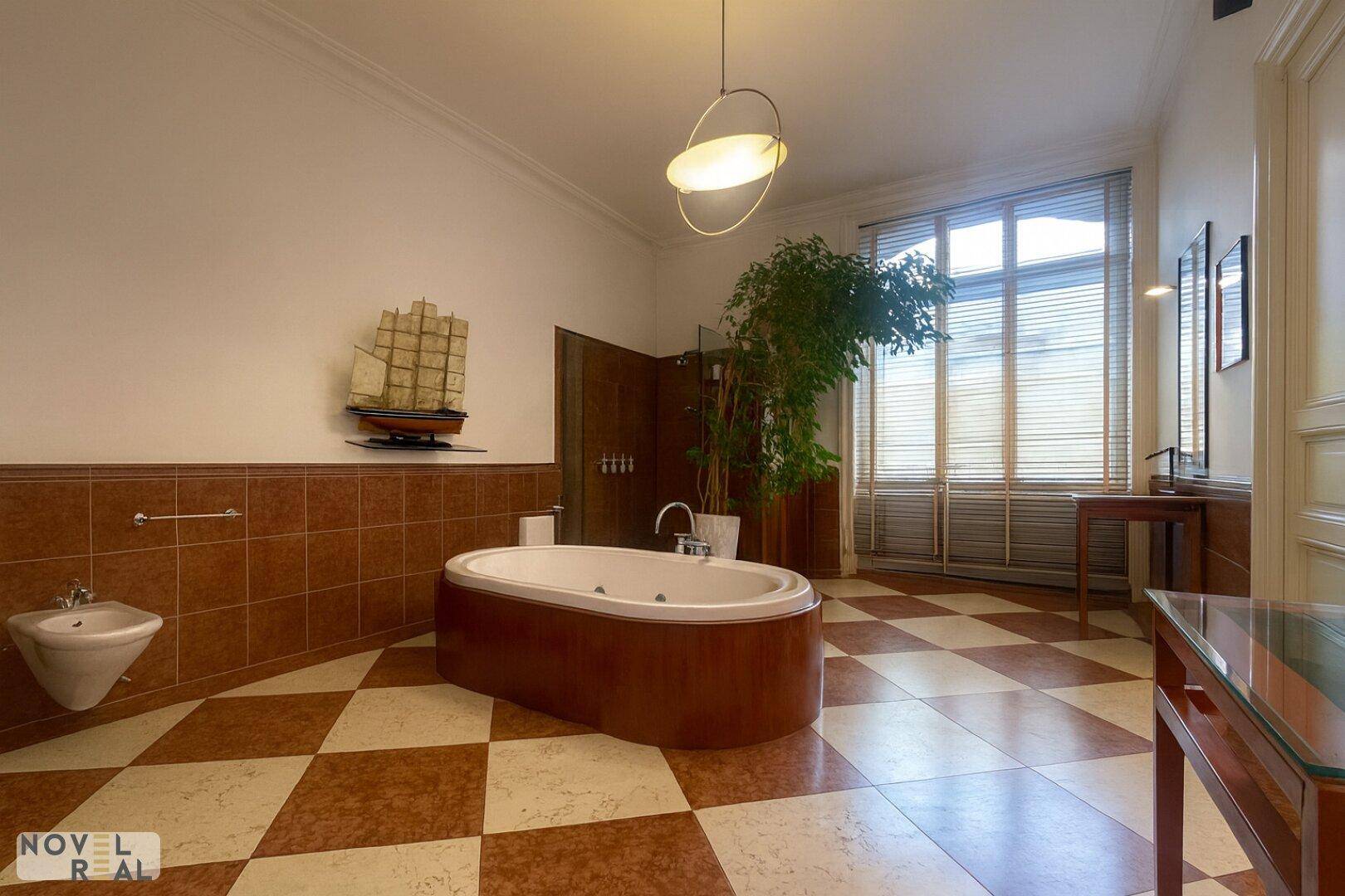 Großes Badezimmer mit freistehender Badewanne, Bidet und kariertem Fliesenboden.