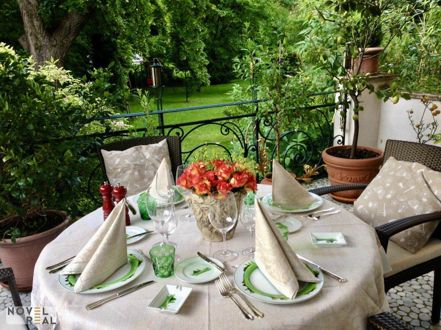 Festlich gedeckter Tisch auf einer Terrasse mit Blick ins Grüne, umgeben von üppiger Vegetation.