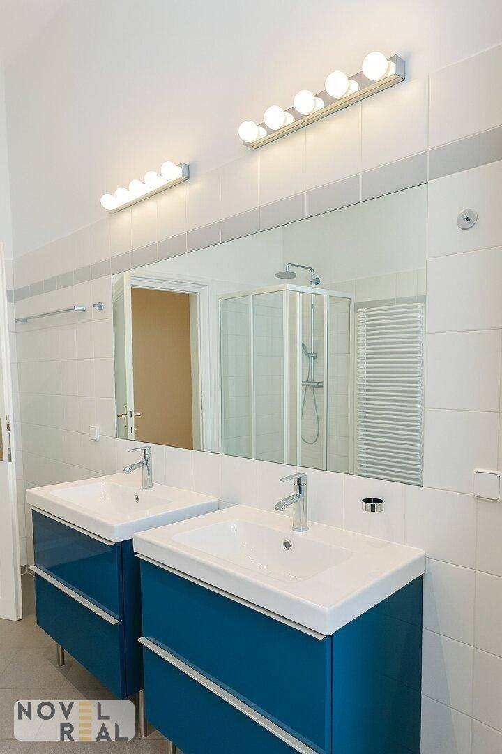 Modernes Badezimmer mit Doppelwaschbecken, großem Spiegel und Duschkabine.