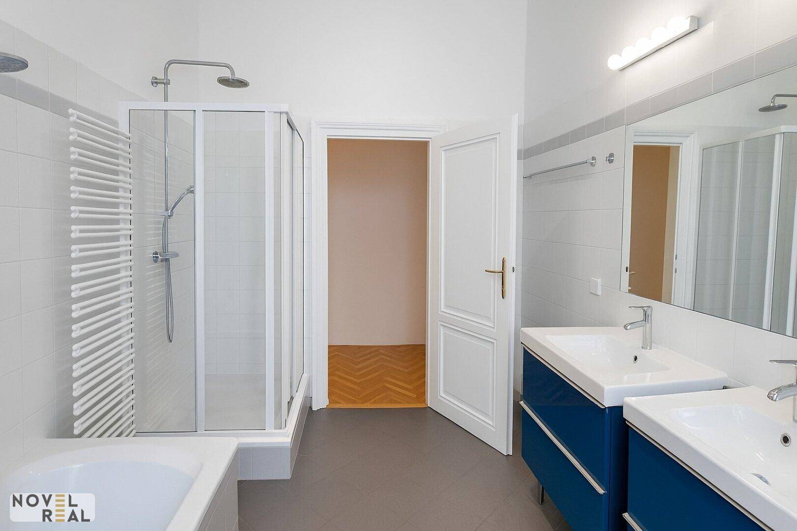 Geräumiges Badezimmer mit Doppelwaschbecken, Duschkabine und Badewanne.