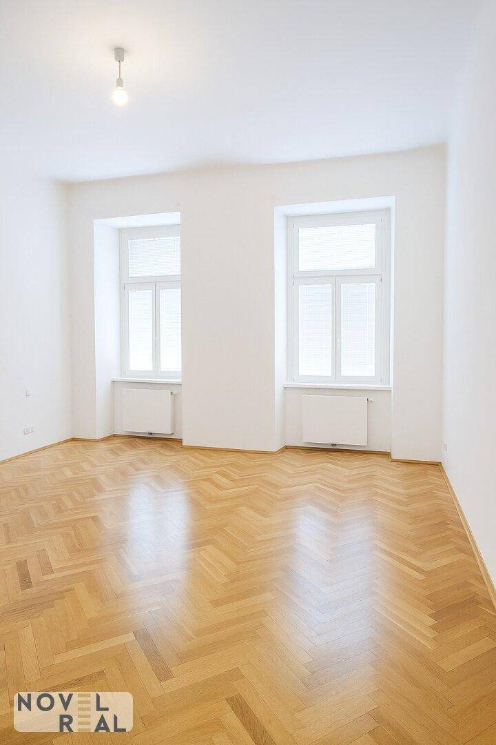 Ruhiges Zimmer mit Fischgrätparkett und zwei Fenstern, ideal als Schlaf- oder Arbeitszimmer.