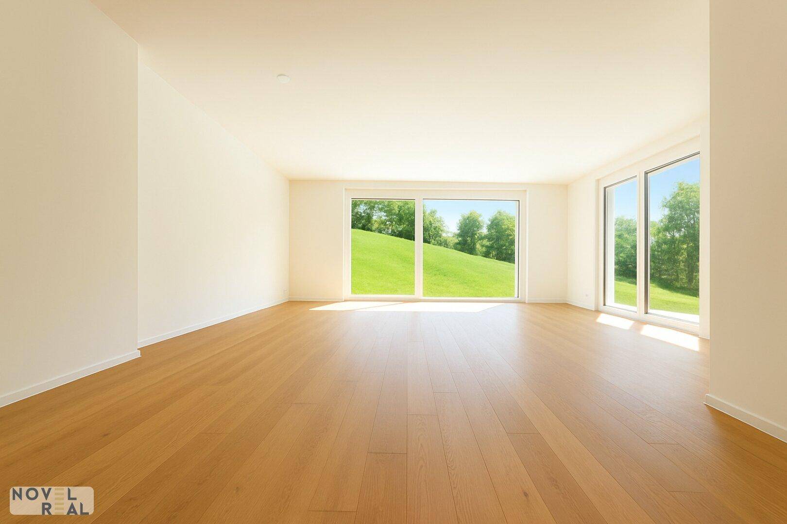 Heller Wohnraum mit Holzboden und großen Fenstern mit Blick auf eine grüne Wiese.