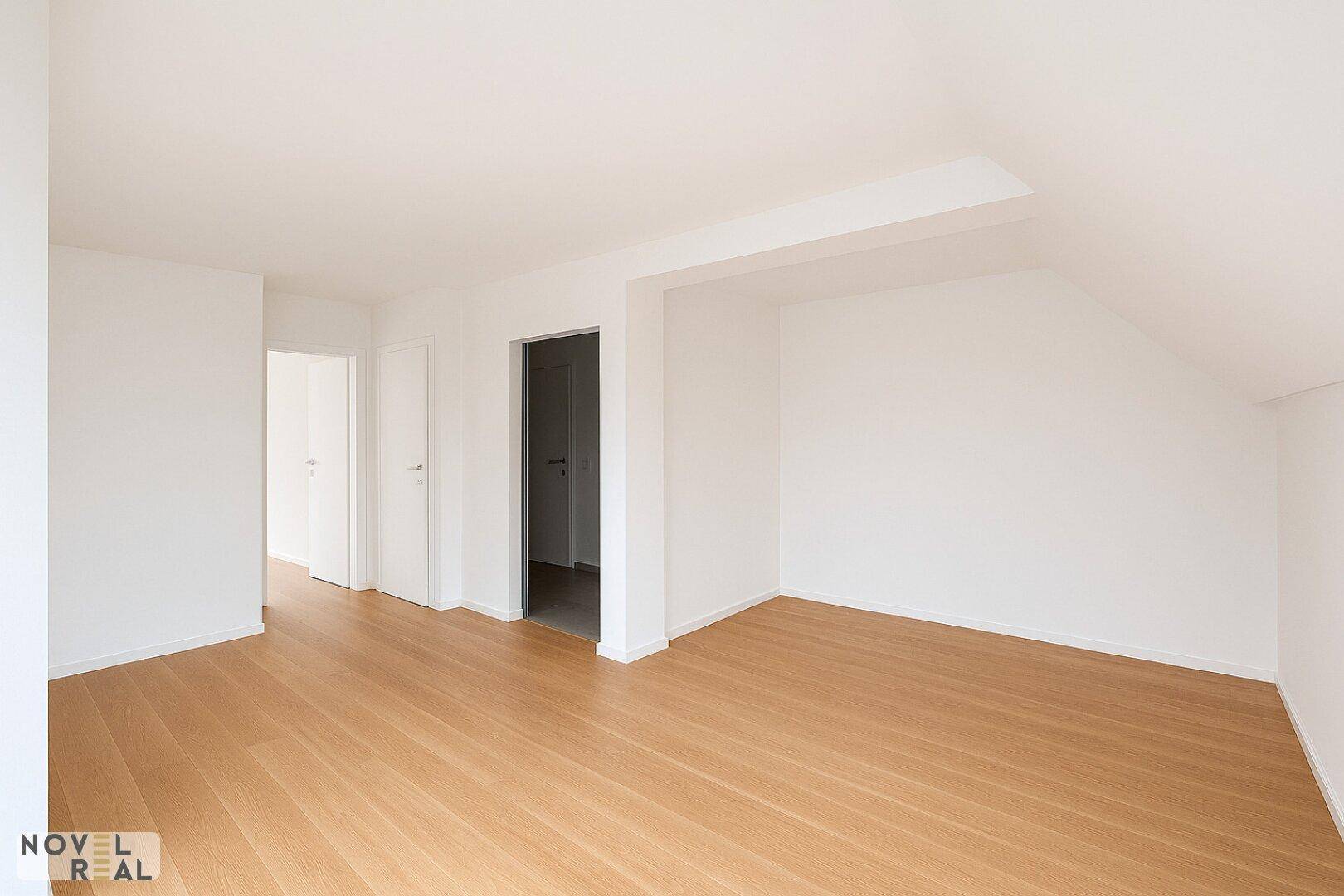 Heller, leerer Raum mit hellem Holzfußboden und weißen Wänden, ideal für individuelle Gestaltung.