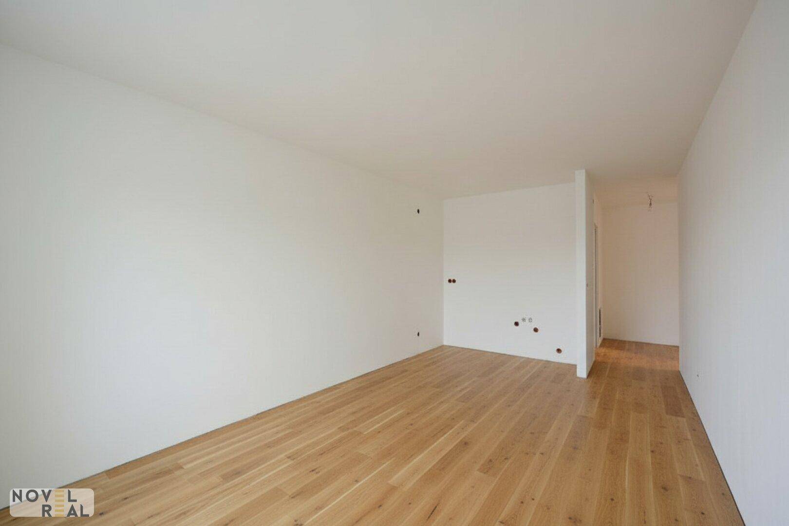 Leerer Raum mit hellen Wänden und Holzfußboden, bereit für die individuelle Gestaltung.