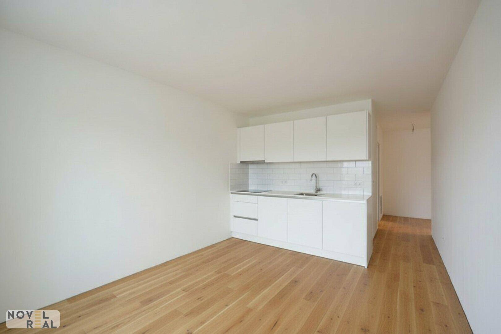 Heller Raum mit moderner Küchenzeile, weißen Schränken und Holzfußboden.