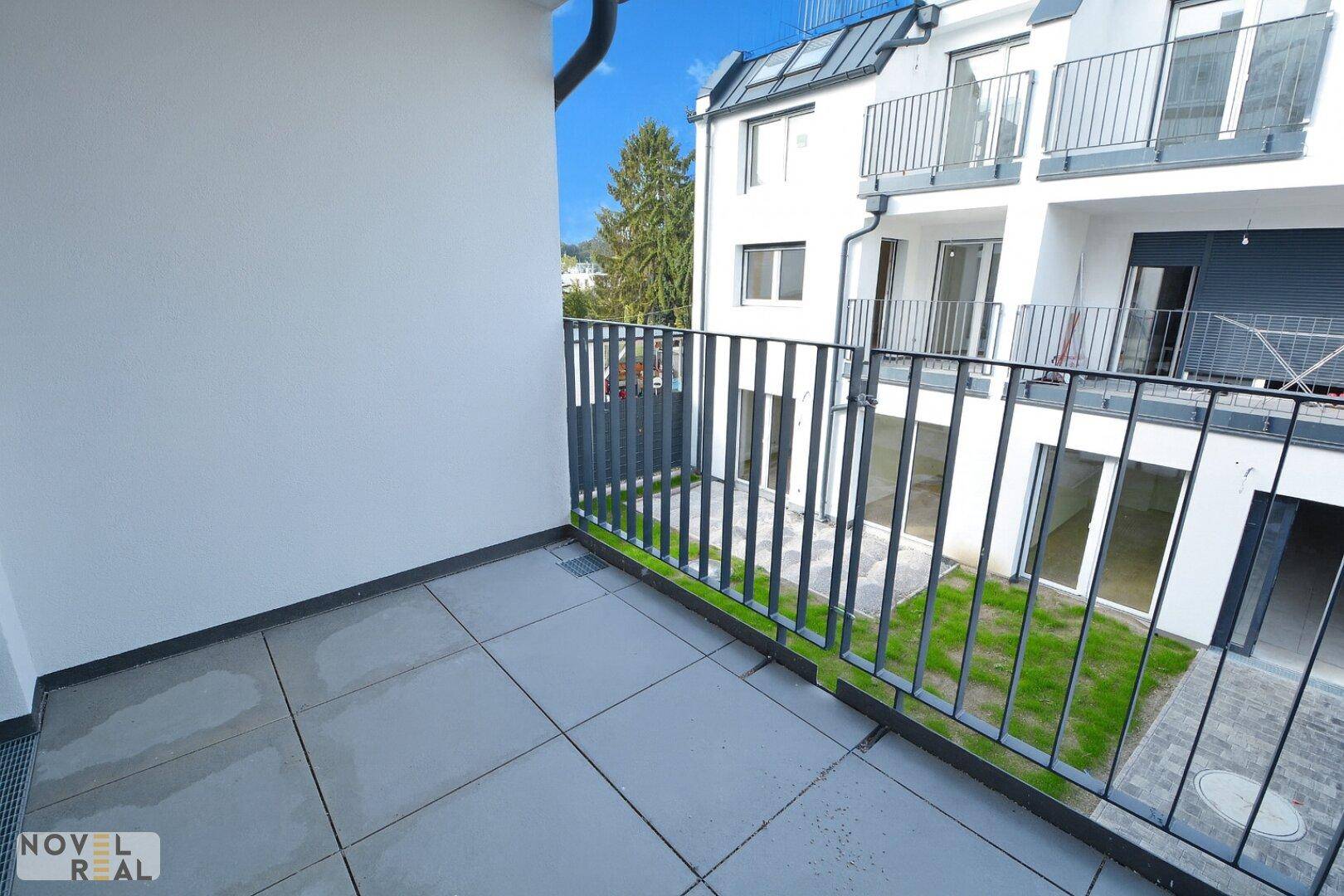 Balkon mit Fliesenboden und Blick auf den Innenhof und die moderne Architektur.