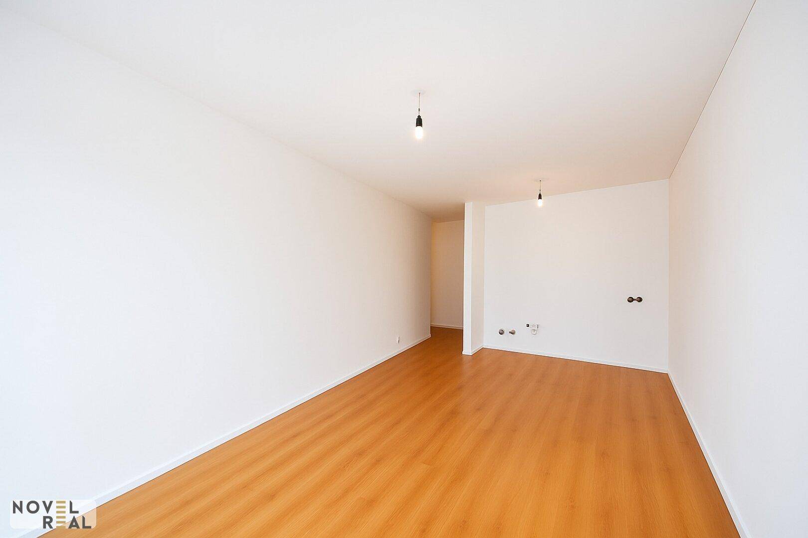 Leerer, heller Raum mit Holzboden und weißen Wänden, bereit für die Einrichtung.
