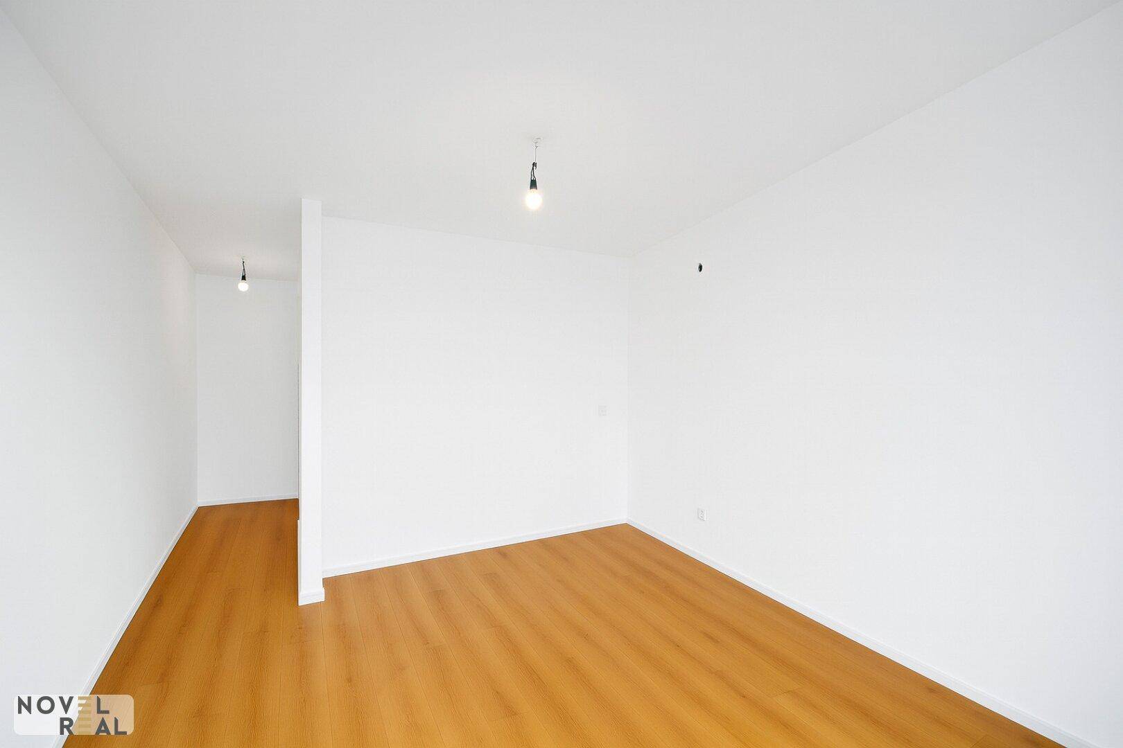 Leerer, heller Raum mit Holzboden und weißen Wänden, ideal für ein Schlafzimmer oder Büro.