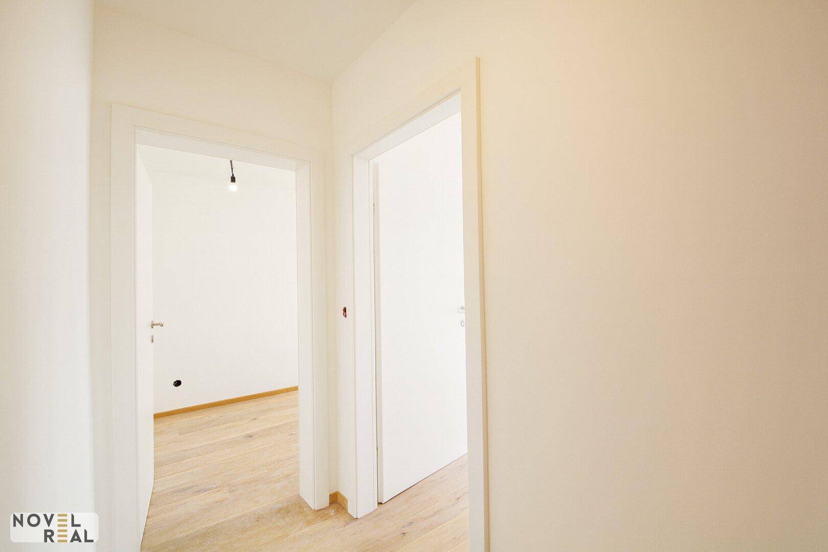 Heller Flur mit Holzboden und Zugang zu weiteren Räumen der Wohnung.