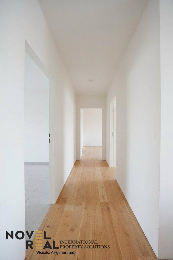 Langer, heller Flur mit Holzboden und weißen Wänden, der zu weiteren Räumen führt.