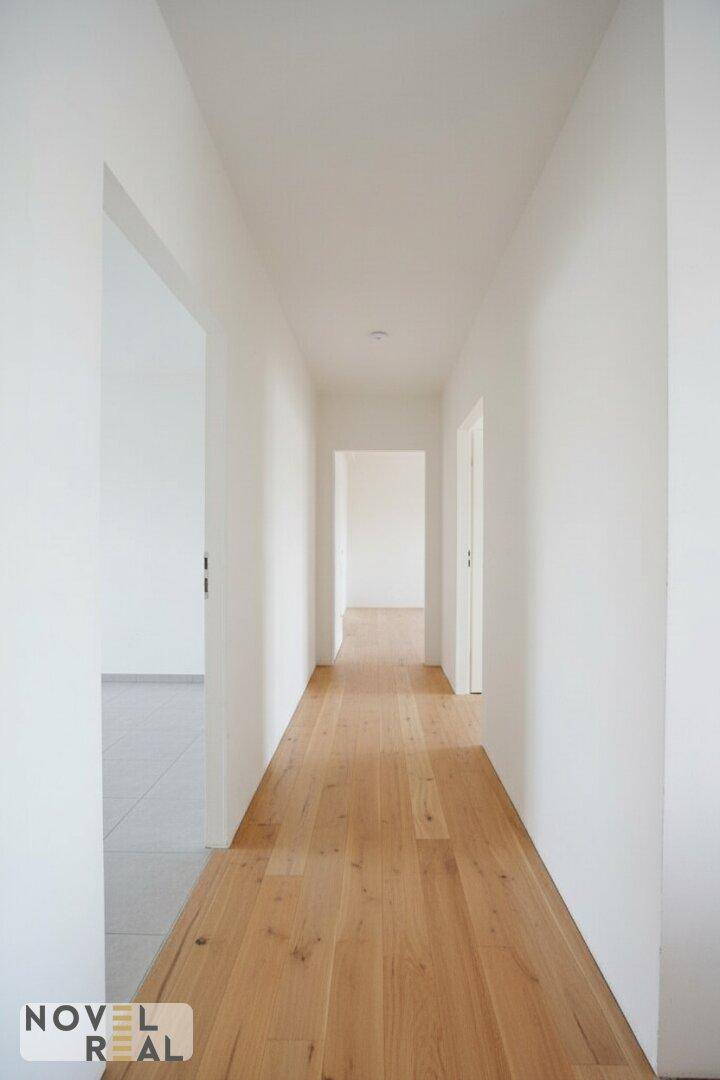 Heller und langer Flur mit elegantem Holzboden, der verschiedene Wohnbereiche miteinander verbindet.