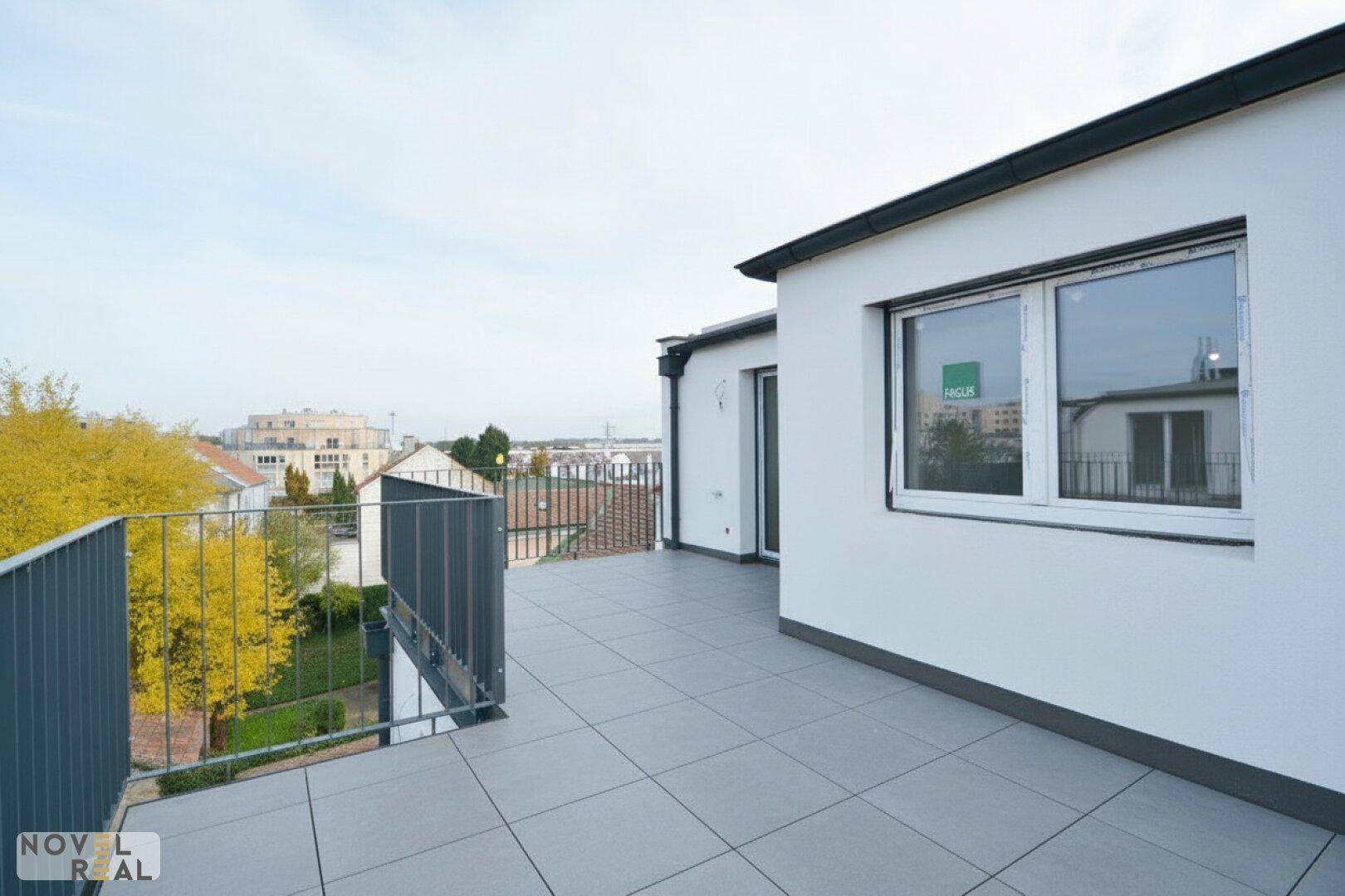 Geflieste Dachterrasse mit modernem Metallgeländer und weitem Ausblick über die Stadtlandschaft.