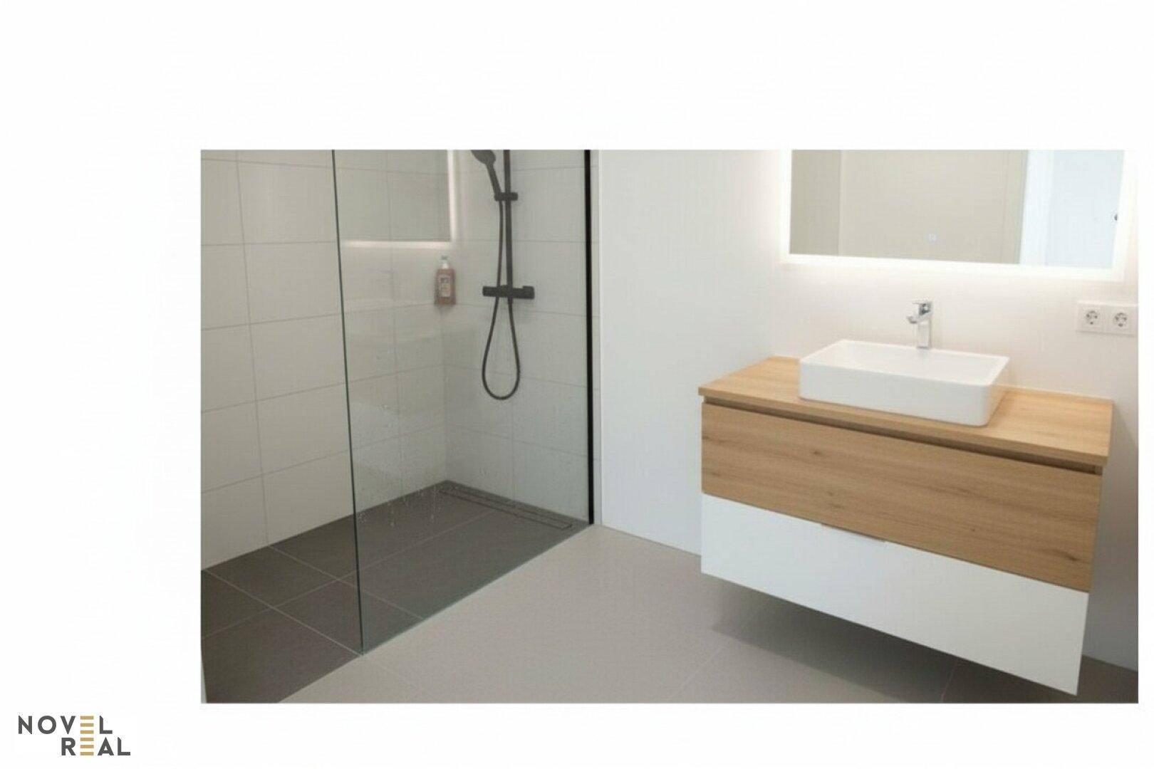 Modernes Badezimmer mit ebenerdiger Dusche, stilvollem Waschtisch und beleuchtetem Spiegel.