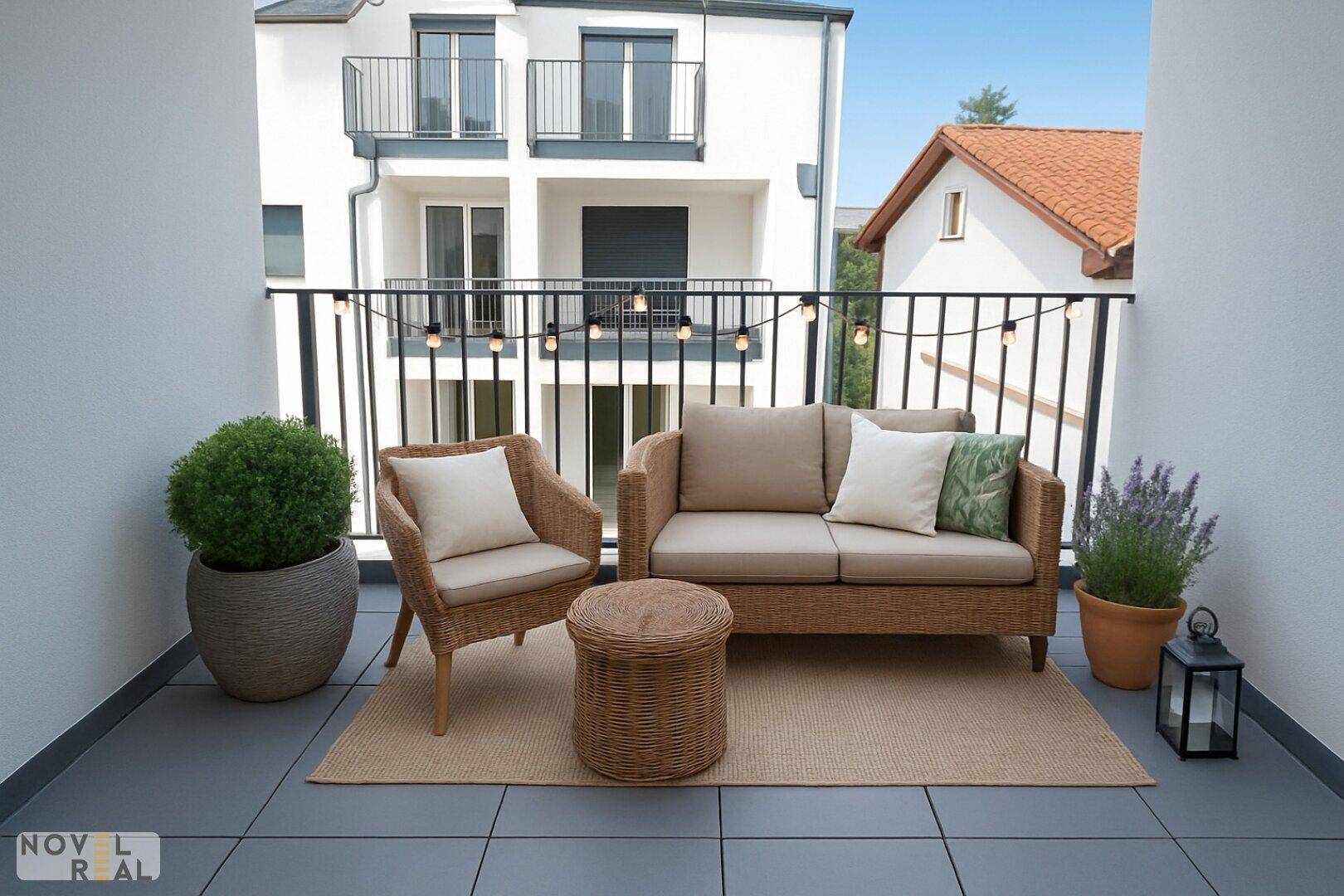 Möblierter Balkon mit Rattanmöbeln, Pflanzen und Blick auf die Umgebung, ideal zum Entspannen.