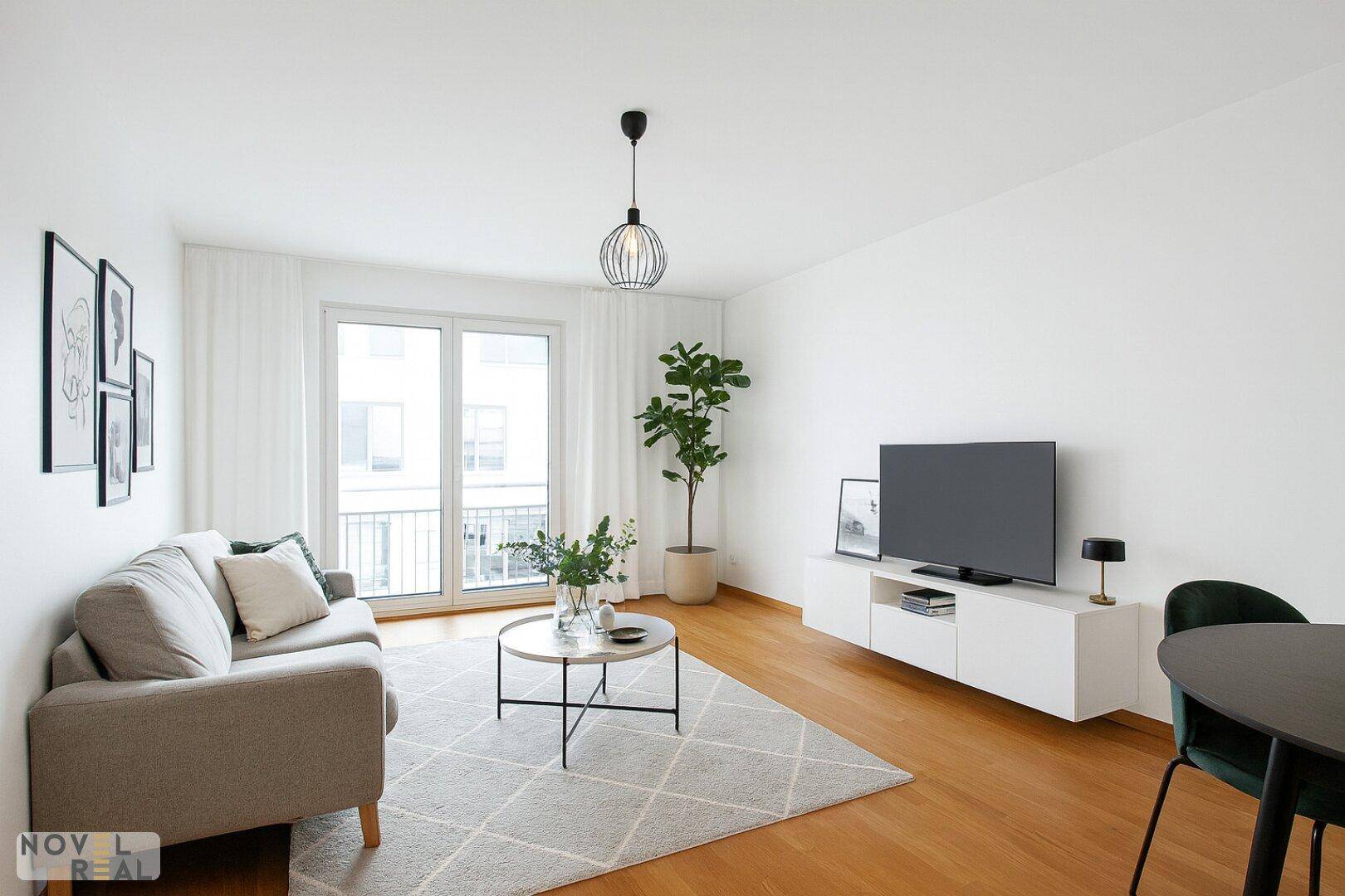 Modern eingerichteter Wohnbereich mit Holzboden, Sofa und Zugang zum Außenbereich.