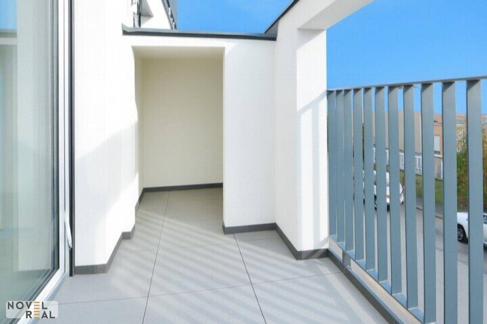 Moderner Balkon mit Fliesenboden und Blick auf die Umgebung, ideal für Entspannung im Freien.