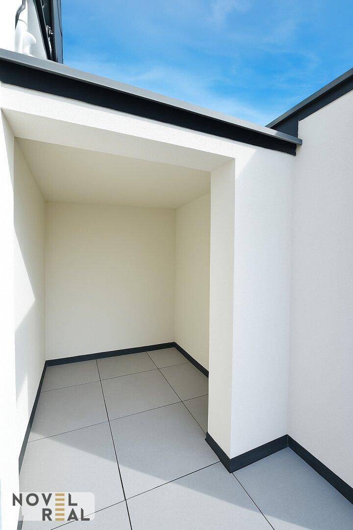 Geschützter Bereich auf dem Balkon mit Fliesenboden und klarem Himmel, bietet Privatsphäre.