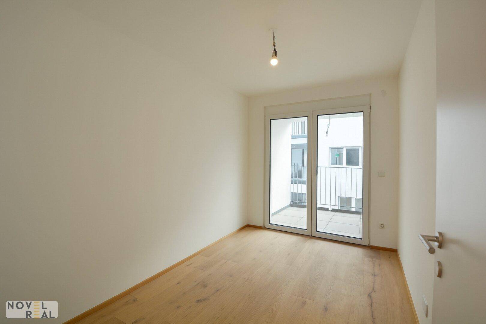 Helles Schlafzimmer mit Holzboden und direktem Zugang zum Balkon, ideal für frische Luft.