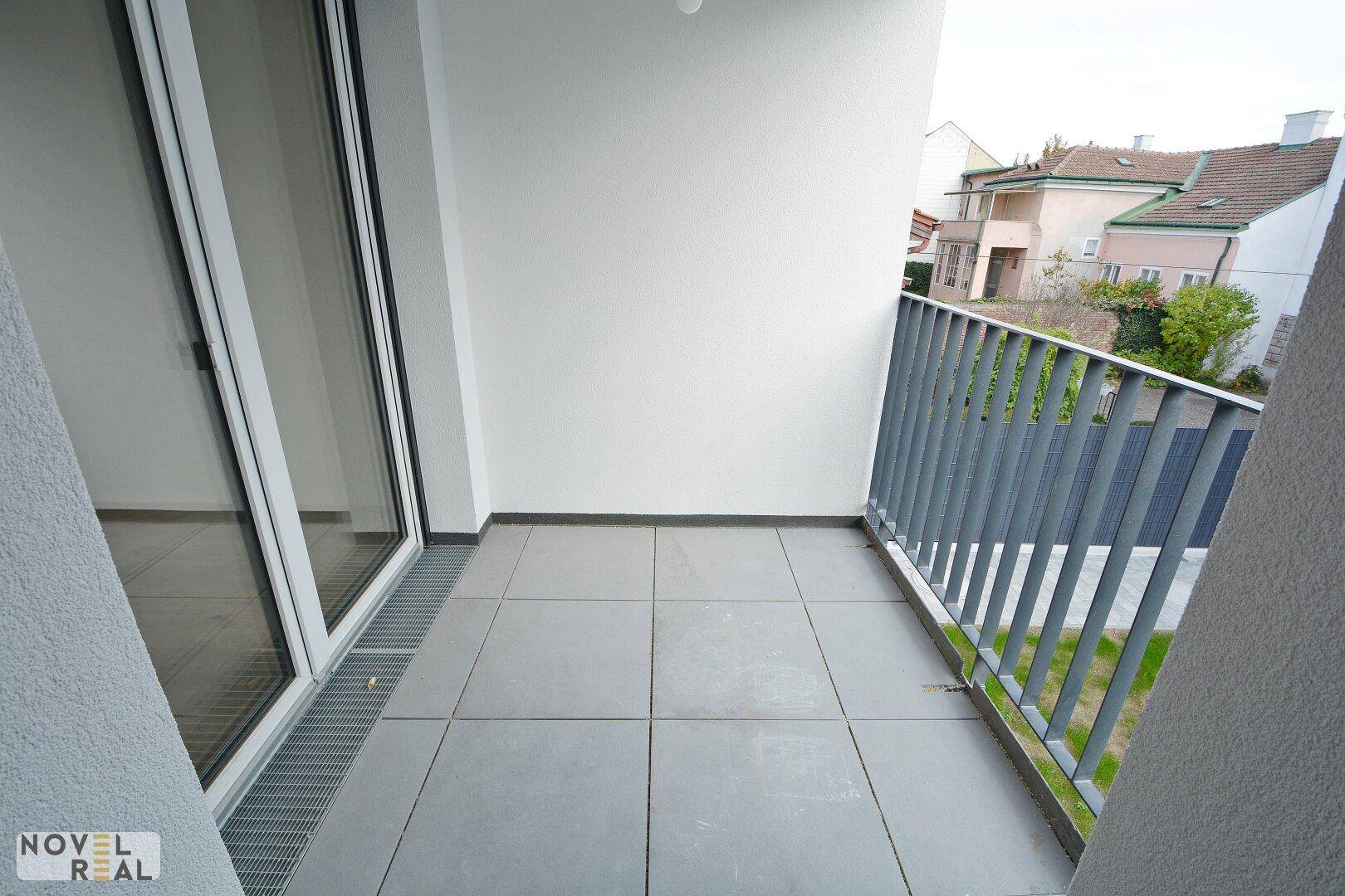 Moderner Balkon mit grauen Fliesen und Metallgeländer, bietet Platz für Entspannung im Freien.