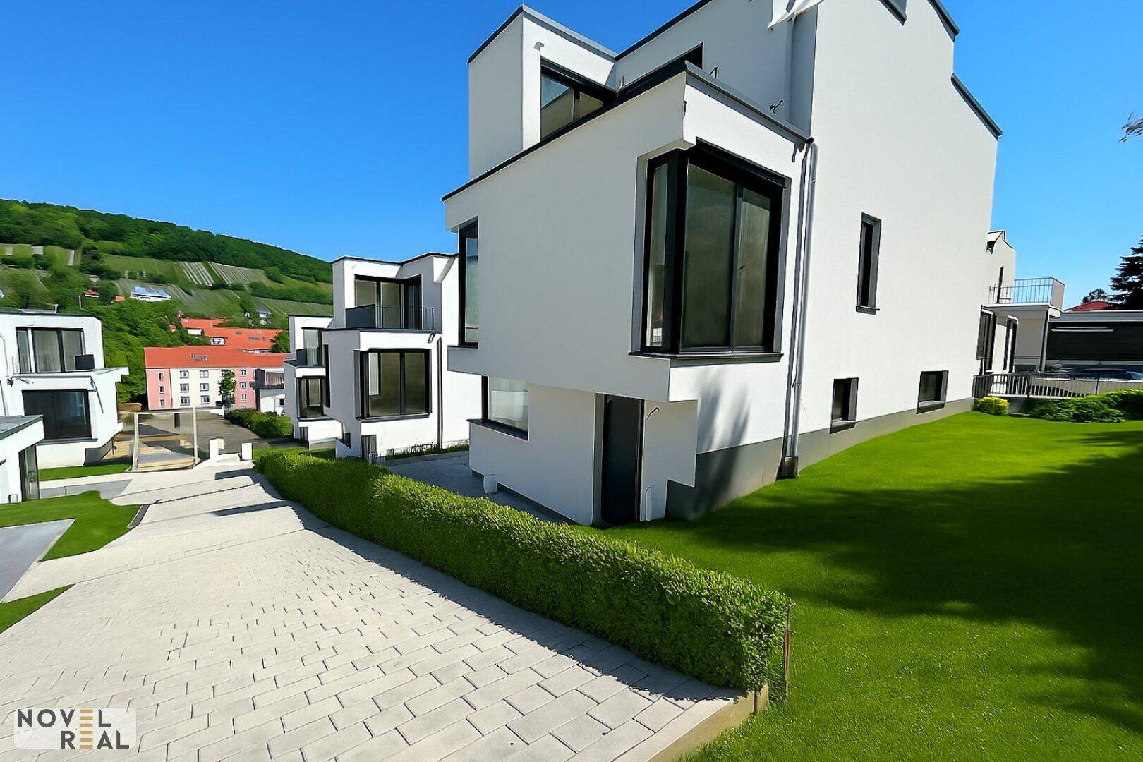 Moderne weiße Villen mit klaren Linien und gepflegten Außenanlagen in sonniger Lage.