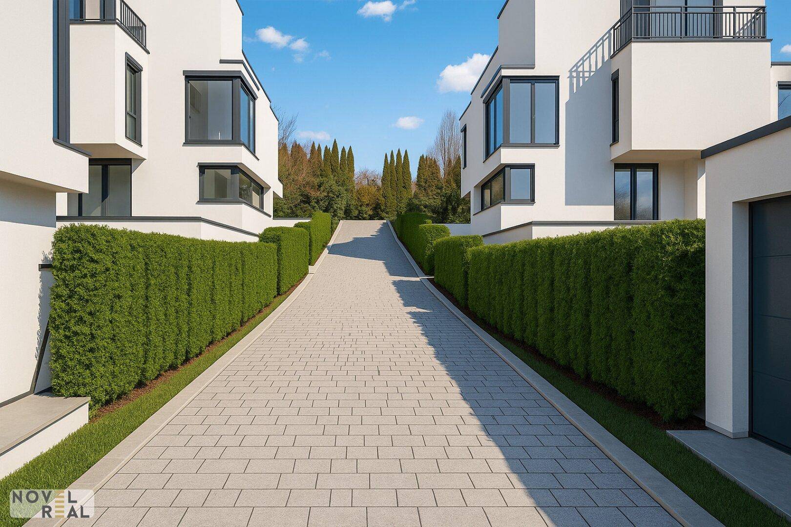 Gepflasterte Auffahrt zwischen modernen Villen, gesäumt von hohen, grünen Hecken.