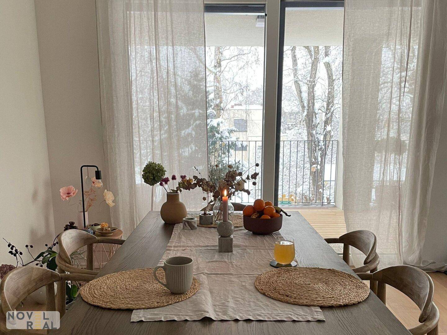 Gemütlicher Essbereich mit großem Holztisch, modernen Stühlen und Blick auf eine verschneite Landschaft.
