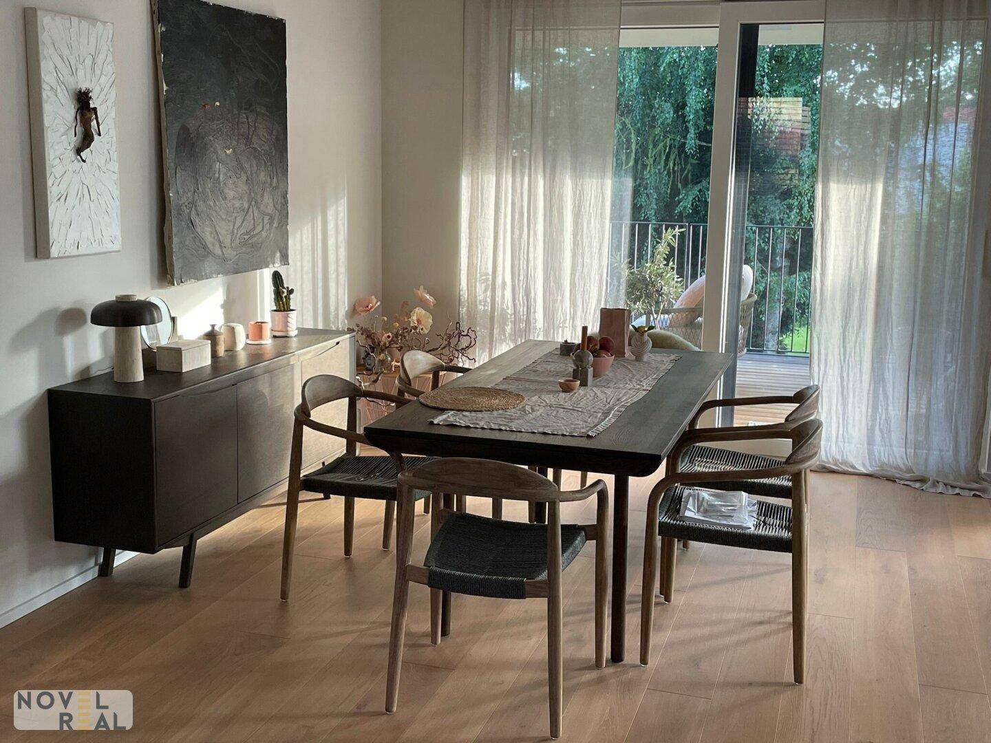 Eleganter Essbereich mit dunklem Holztisch, passenden Stühlen und Zugang zum Balkon.
