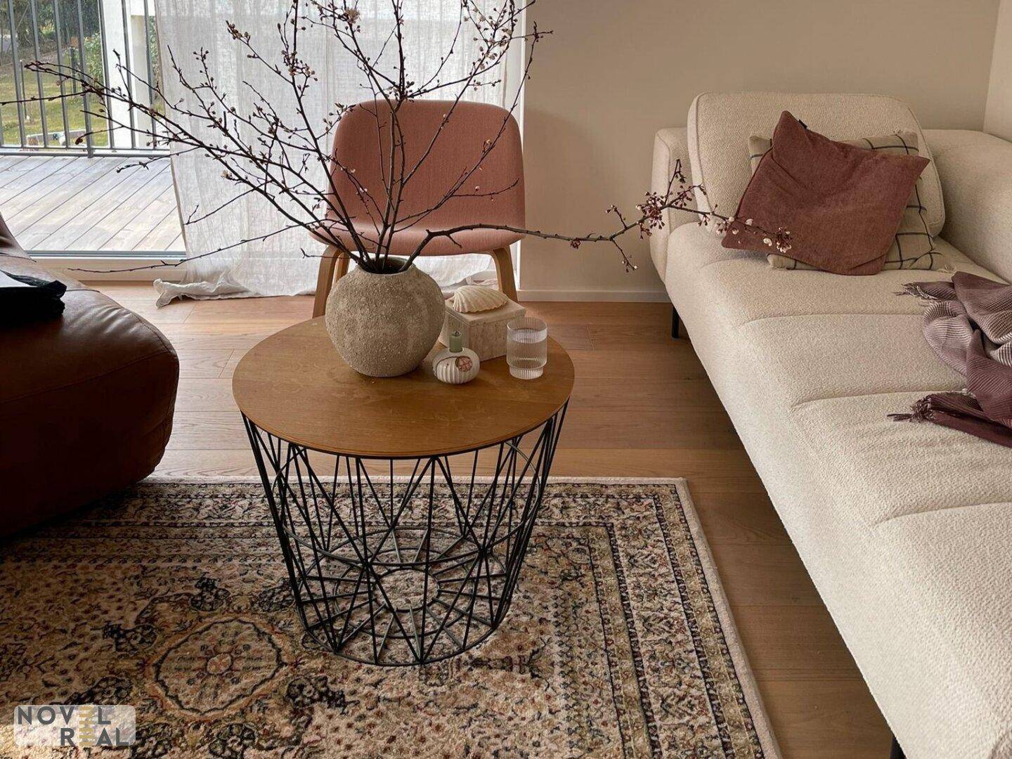 Detailaufnahme des Wohnzimmers mit modernem Couchtisch, Vase und Teppich.