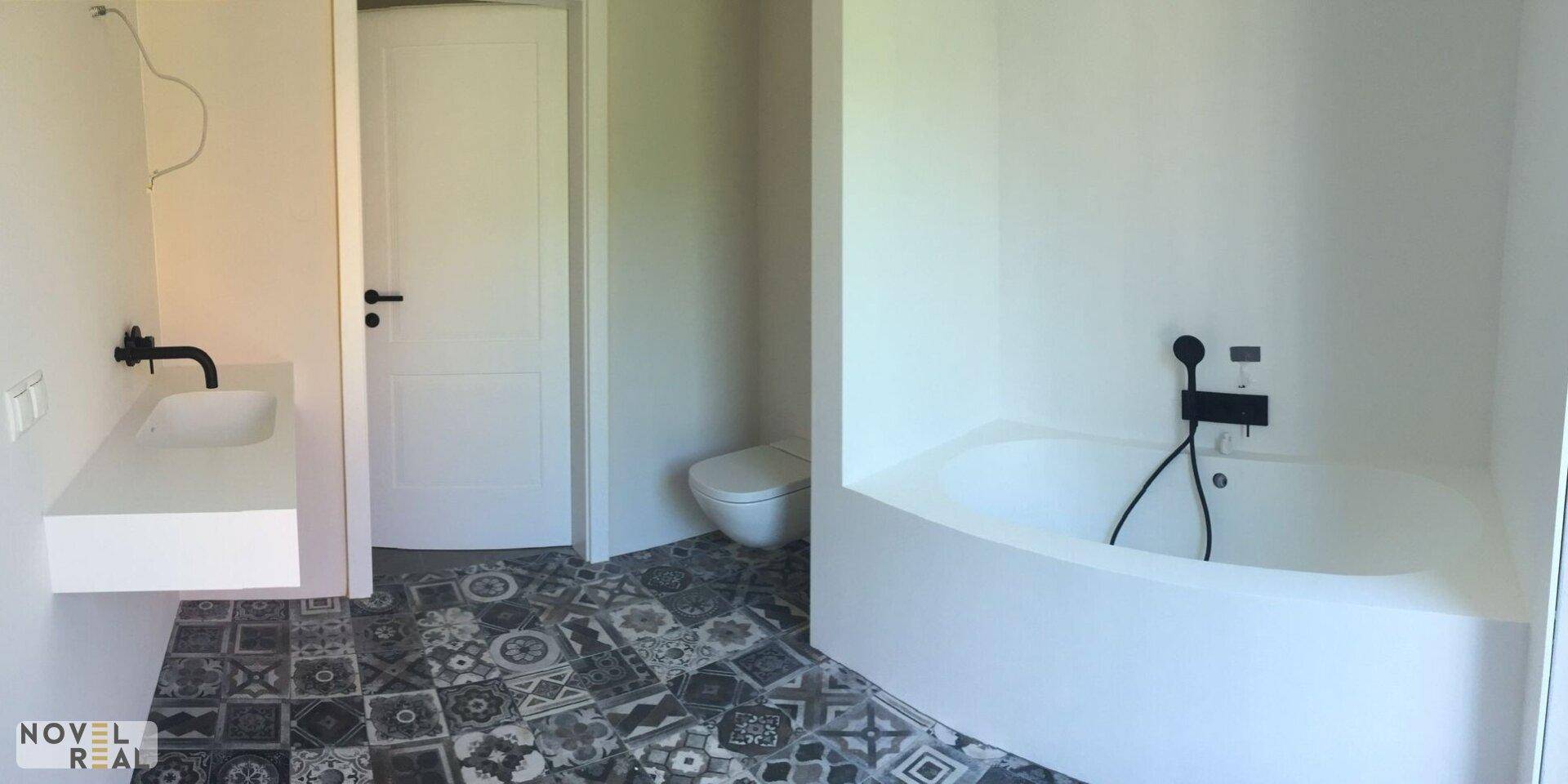 Geräumiges Badezimmer mit Badewanne, Waschbecken und WC, ausgestattet mit gemusterten Fliesen.