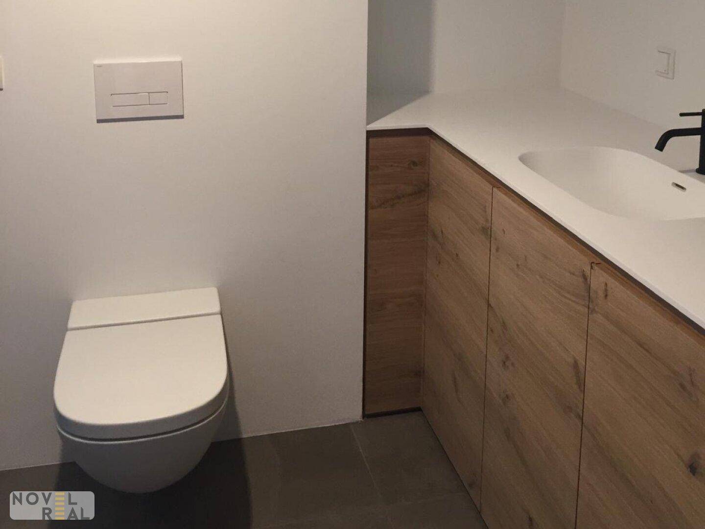 Modernes Badezimmer mit Wand-WC und elegantem Waschtisch mit Holzunterschrank.