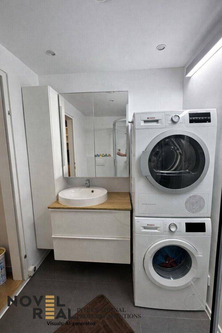 Badezimmer mit Waschmaschine und Trockner, Waschbecken und Spiegelschrank.