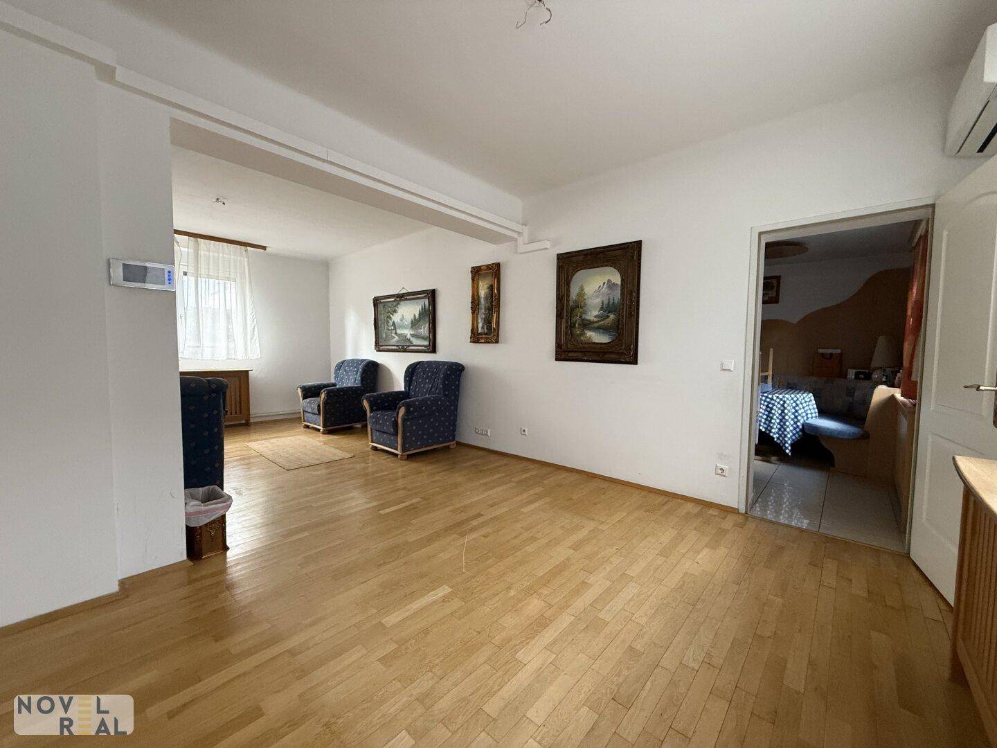 Helles Wohnzimmer mit Parkettboden und bequemen blauen Sesseln, ideal zum Entspannen.