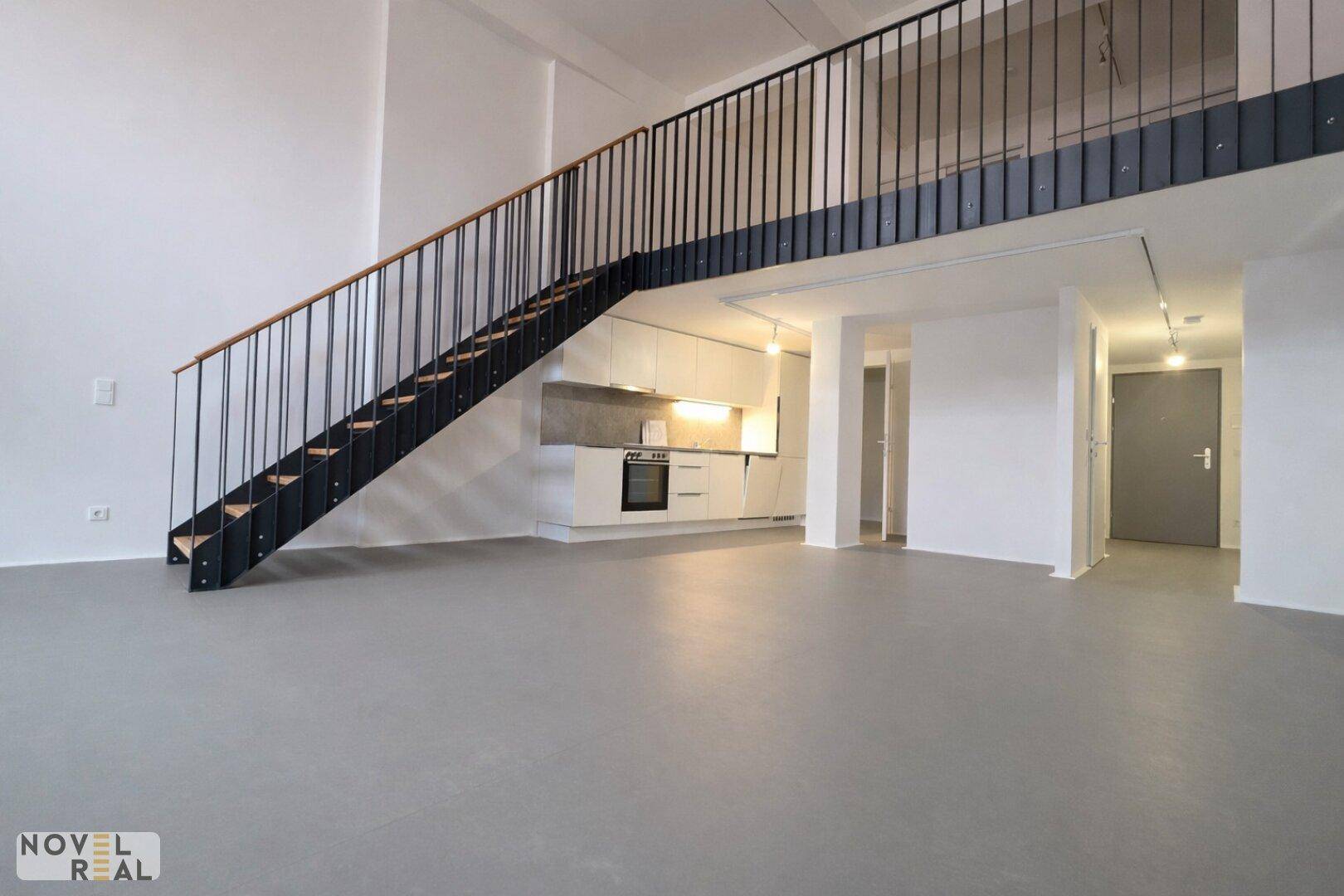 Heller Wohnbereich mit integrierter Küche, hohen Decken und moderner Treppe.