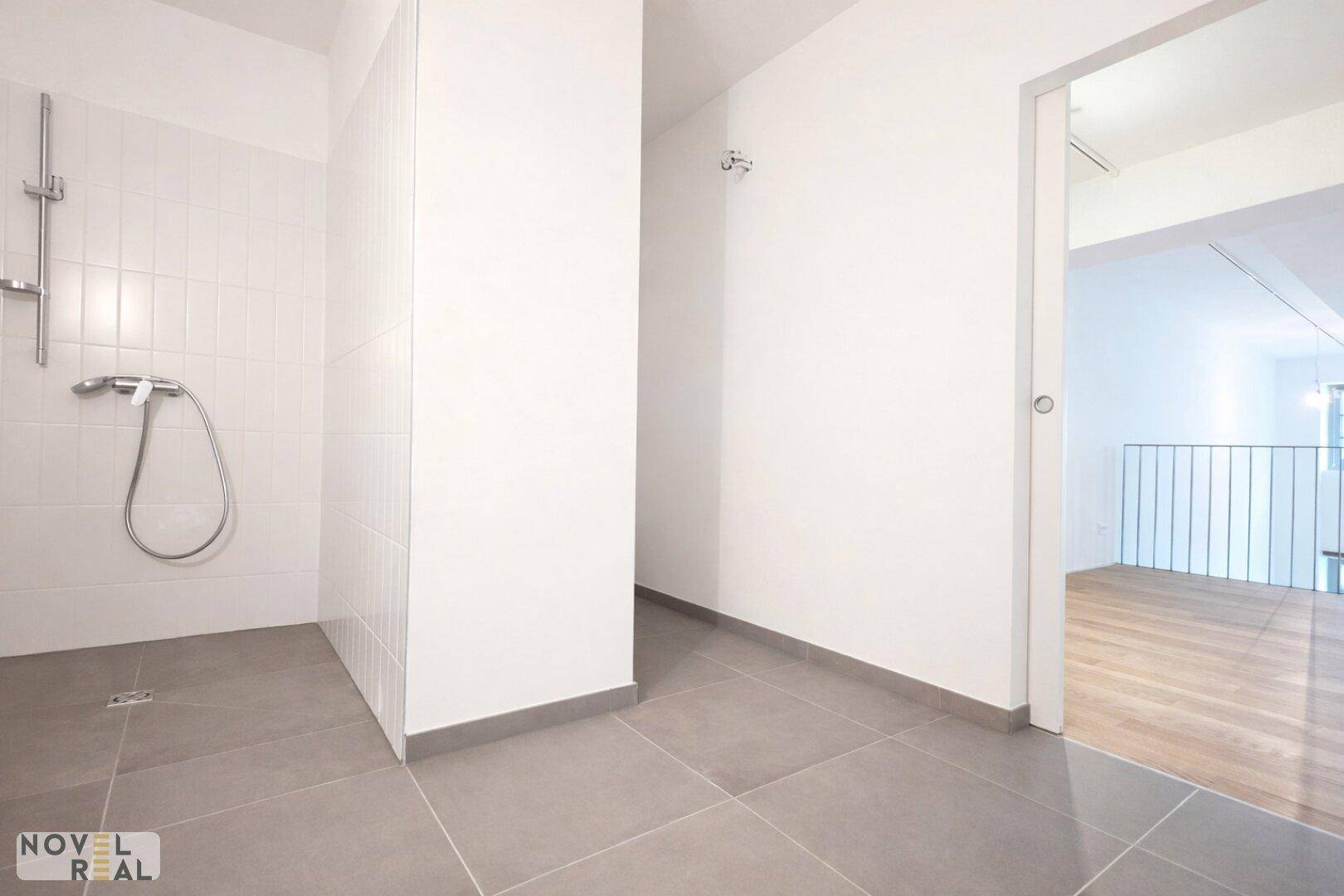 Modernes Badezimmer mit ebenerdiger Dusche und grauen Fliesen.