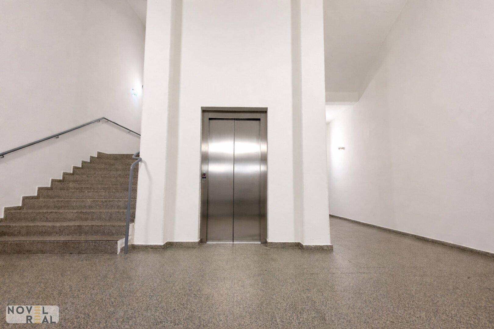 Heller Flur mit Aufzug und Treppenhaus in einem modernen Gebäude.