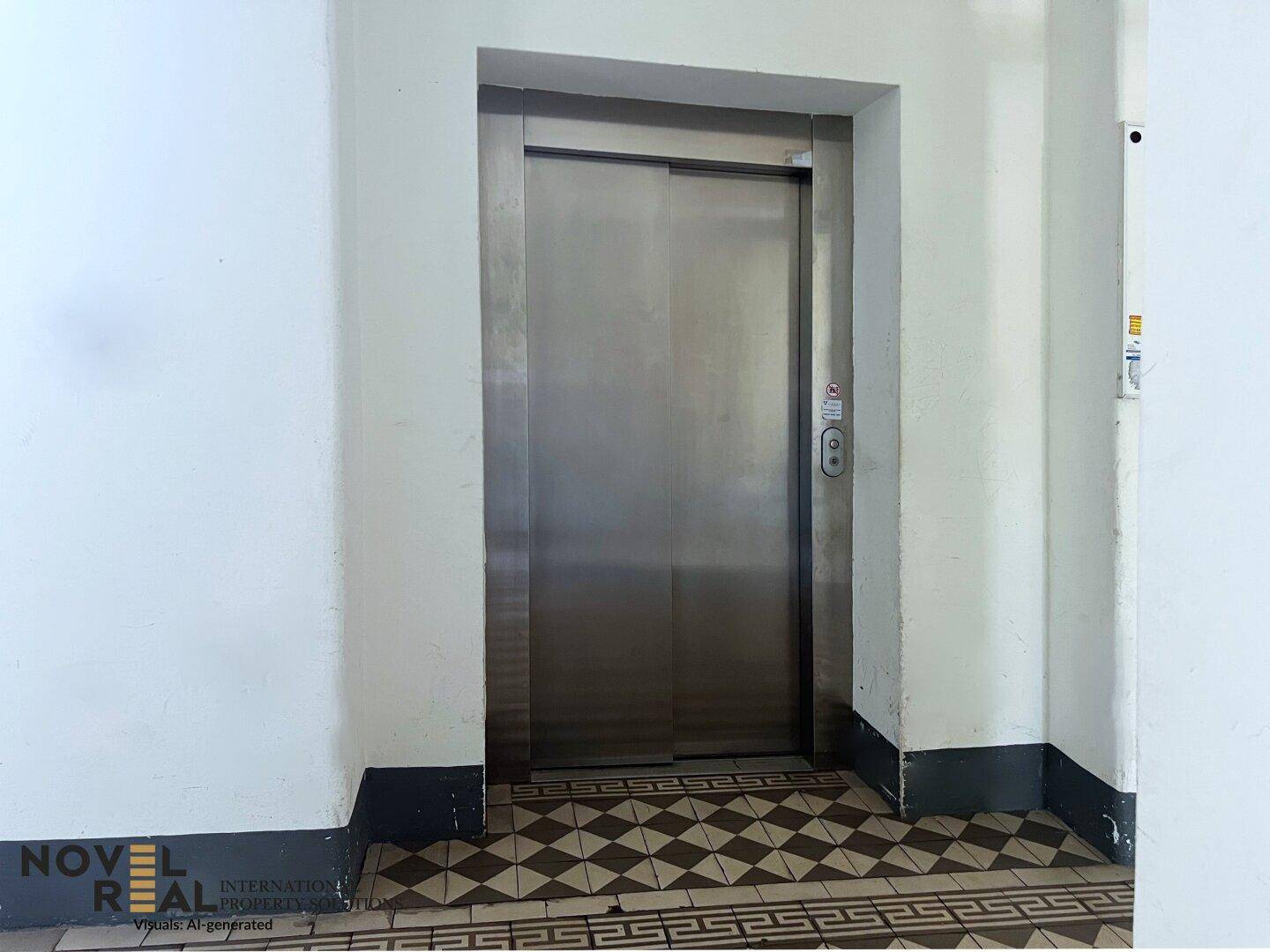 Moderner Aufzug in einem Gebäude mit gemustertem Fliesenboden im Eingangsbereich.